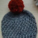 Handmade grey crochet baby pom pom beanie with textured pattern and red fluffy pom pom