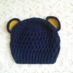 Handmade navy blue crochet baby bear ear cap with yellow inner ear detailing