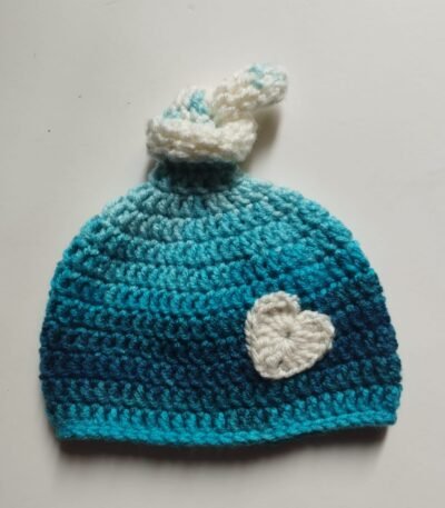 Handmade blue crochet baby knot cap with white heart appliqué and two-tone winter design