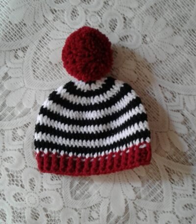 Handmade black and white striped crochet baby beanie with red pom pom and contrast edge