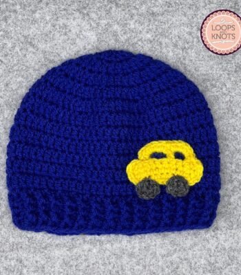 Handmade blue crochet baby beanie cap with yellow car appliqué design for winter