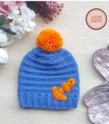 Handmade blue crochet baby beanie cap with orange pom pom and decorative crochet detail